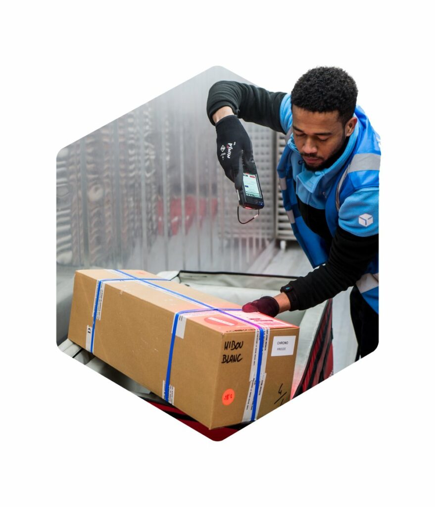Livreur Chronofresh scannant un colis ร lโaide dโun terminal portable, assurant le suivi prรฉcis et la traรงabilitรฉ des livraisons de produits frais.